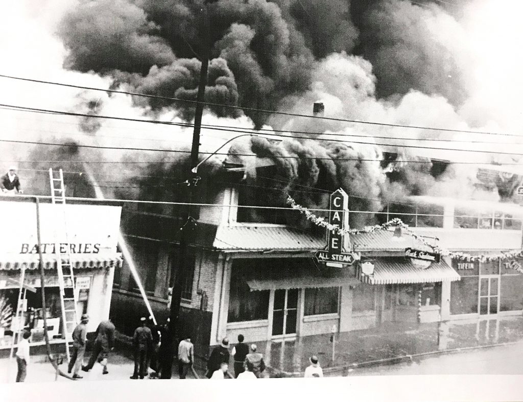 In 1962, the businesses next to Bennett Auto Supply caught fire and burned down. The fire began in what was once the theater and destroyed the block, including the original All Steak Cafe. The alley, which still exists on the south side of Bennett, kept the fire from spreading. This photo shows a young Doug Bennett on the roof of the building working to prevent the fire from spreading as the fire department fought the blaze. (Bennett family)
